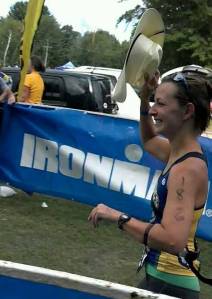 Susan crossing the finish line of her first Half Ironman with a cowboy hat from Linsey Corbin!