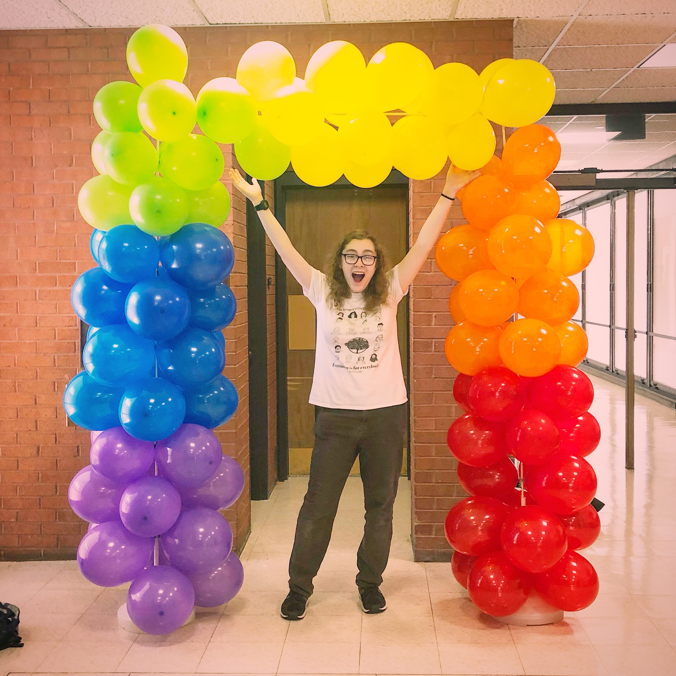Student leader, Autumn, standing with a balloon arch we made to celebrate the opening of UMBC's first multi-user all-gender restroom.